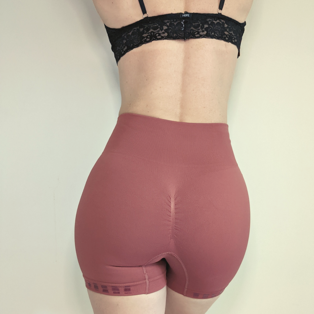 Model wearing Love Saia non slip slip shorts in ochre, view from behind.